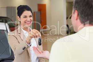 Smiling businesswoman giving car key to happy customer