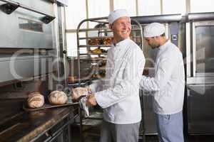 Happy baker holding tray of fresh bread