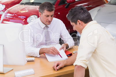 Salesman showing client where to sign the deal