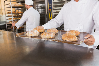 Close up of baker holding tray of bread