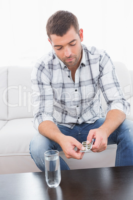 Hungover man with his medicine laid out on coffee table