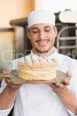 Baker showing freshly baked loaf