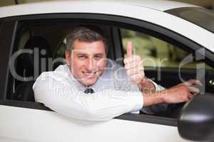Smiling man sitting in his car giving thumbs up