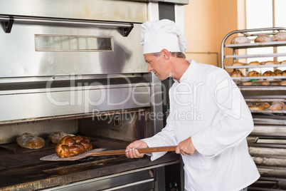 Focused baker taking out fresh loaf