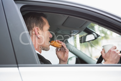 Businessman having coffee and doughnut on the phone