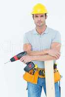 Confident carpenter with wooden plank and drill machine