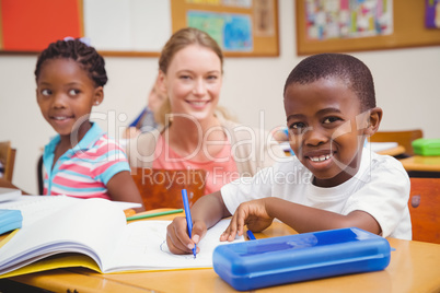 Pretty teacher helping pupil in classroom