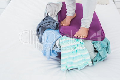 Woman standing on baggage to close it