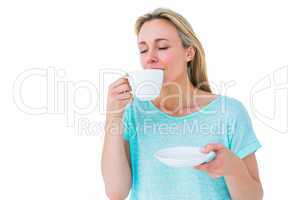 Peaceful blonde drinking hot beverage with eyes closed