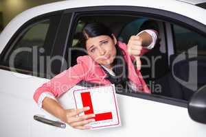 Woman gesturing thumbs down holding a learner driver sign
