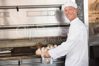 Happy baker holding tray of fresh bread Happy baker holding tray of fresh bread