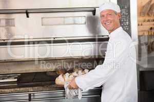 Happy baker holding tray of fresh bread