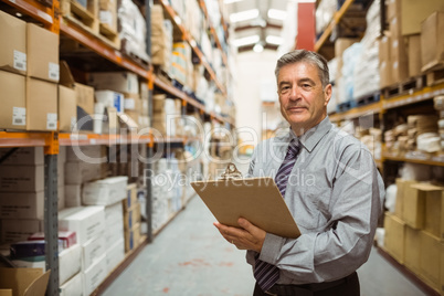 Smiling warehouse manager holding a clipboard