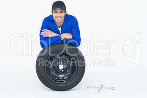 Handsome mechanic leaning on tire