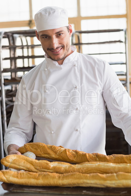 Baker looking at freshly baked baguettes