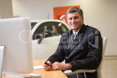 Smiling businessman sitting at his desk holding a car key