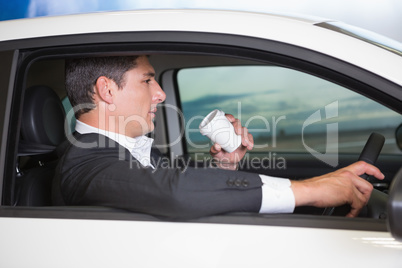 Serious businessman drinking coffee while driving