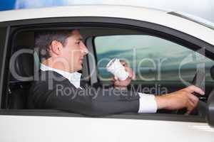 Serious businessman drinking coffee while driving