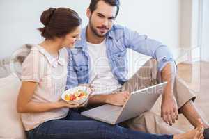 Cute couple sitting on floor using laptop