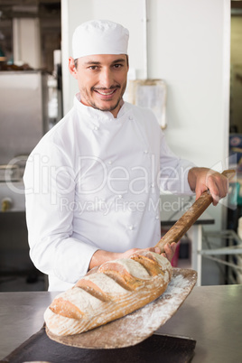 Happy baker taking out fresh loaf