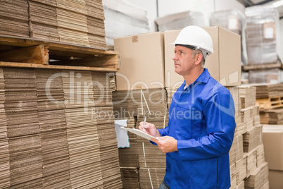 Warehouse worker checking his list on clipboard