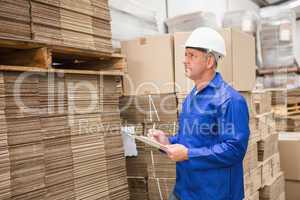 Warehouse worker checking his list on clipboard