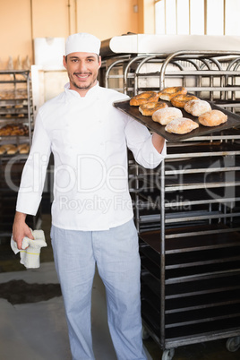 Baker holding tray of bread