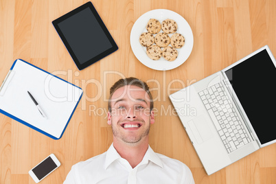 Man lying on floor surrounded by various objects at home