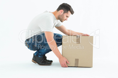 Delivery man crouching while picking cardboard box