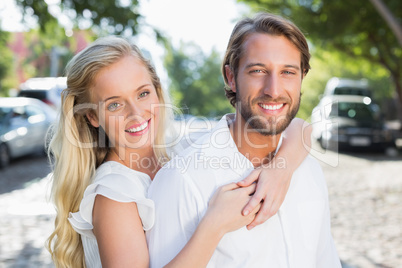 Attractive couple hugging each other and smiling at camera