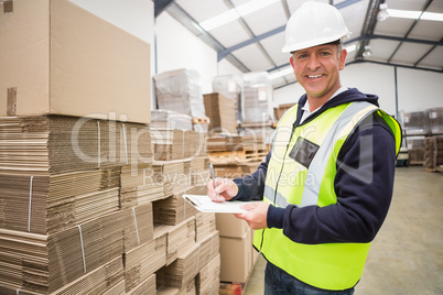 Warehouse worker checking his list on clipboard