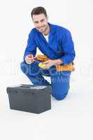 Happy repairman kneeling by toolbox