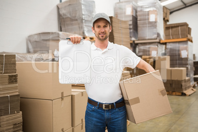 Delivery man with box and clipboard in warehouse