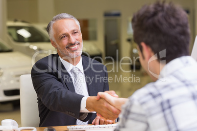 Smiling salesman shaking a customer hand