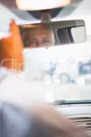 Businessman looking in an interior car mirror