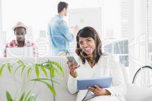 Smiling businesswoman using laptop and mobile on couch