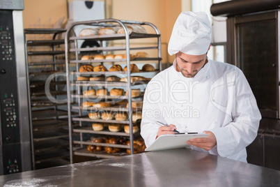 Focused baker writing on clipboard