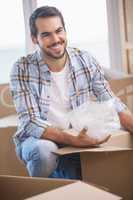 Smiling man unpacking cardboard boxes