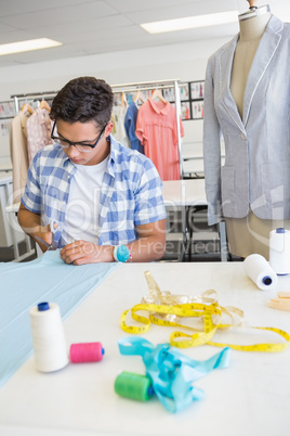 Fashion student cutting fabric with pair of scissors