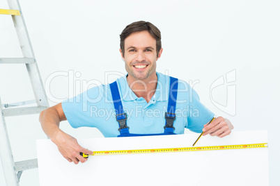 Happy carpenter measuring blank bill board