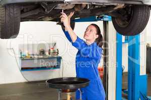 Mechanic adjusting something under car