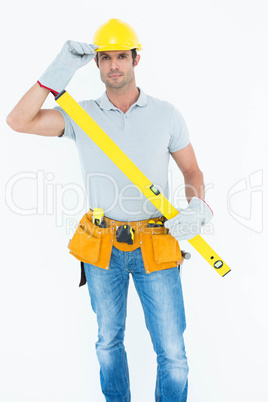 Carpenter holding spirit level while wearing hard hat