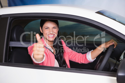Smiling woman driving while giving thumbs up