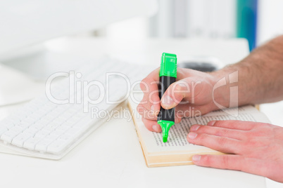 Hands of businessman highlighting a book