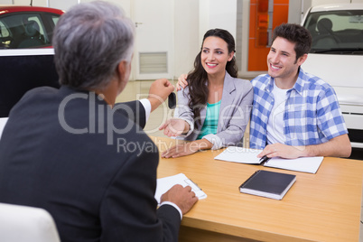 Salesman giving car keys to a couple