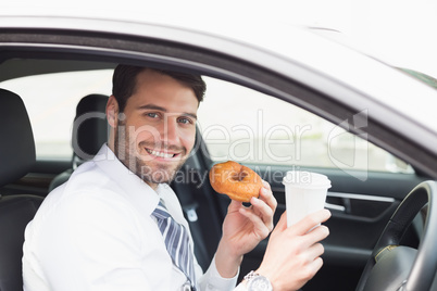 Young businessman having coffee and doughnut