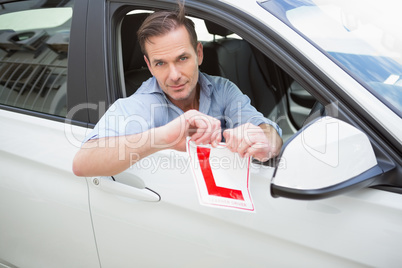 Smiling male driver tearing up his L sign