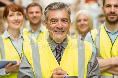 Warehouse team with arms crossed wearing yellow vest