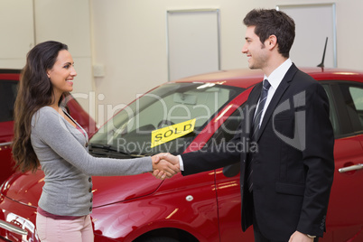 Person shaking hands in front of a sold car