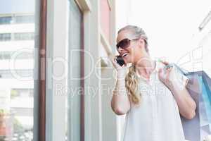 Pretty blonde making a call holding shopping bags